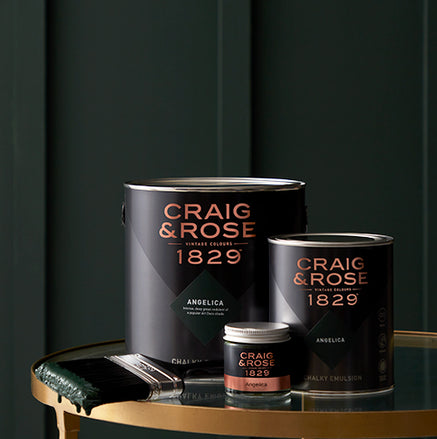 Craig & Rose 1829 Vintage collection paint tins and brush sitting on a gold and glass table