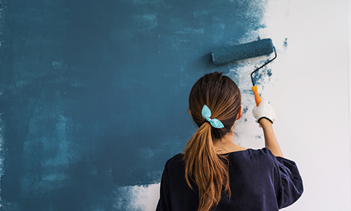 Women painting a wall blue with a paint roller