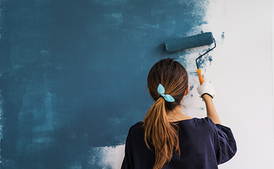 Women painting a wall blue with a paint roller